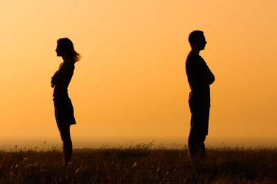 Kobieta i mężczyzna stoją do siebie odwróceni plecami, w tle zachód słońca