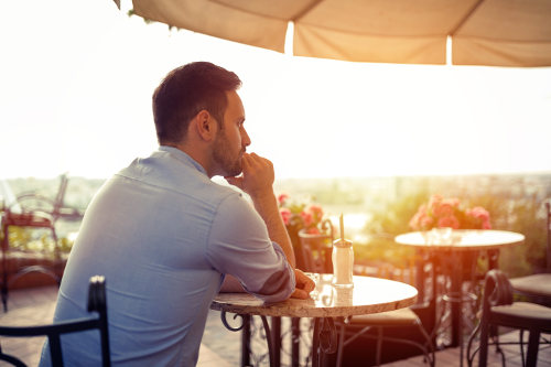 Siedzący przy stoliku w kawiarni mężczyzna czeka na kobietę