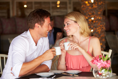 Mężczyzna z kobietą siedzą przy stoliku w kawiarni i piją kawę