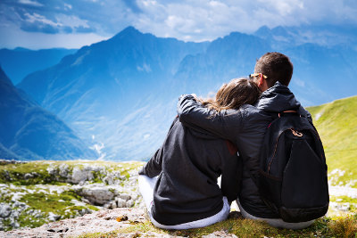 Para siedząca na szczycie góry i patrząca na panoramę gór