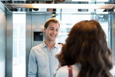 Młody mężczyzna uśmiecha się do kobiety w windzie