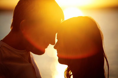 Kobieta i mężczyzna na tle zachodzącego słońca, patrzący na siebie, bliscy sobie emocjonalnie